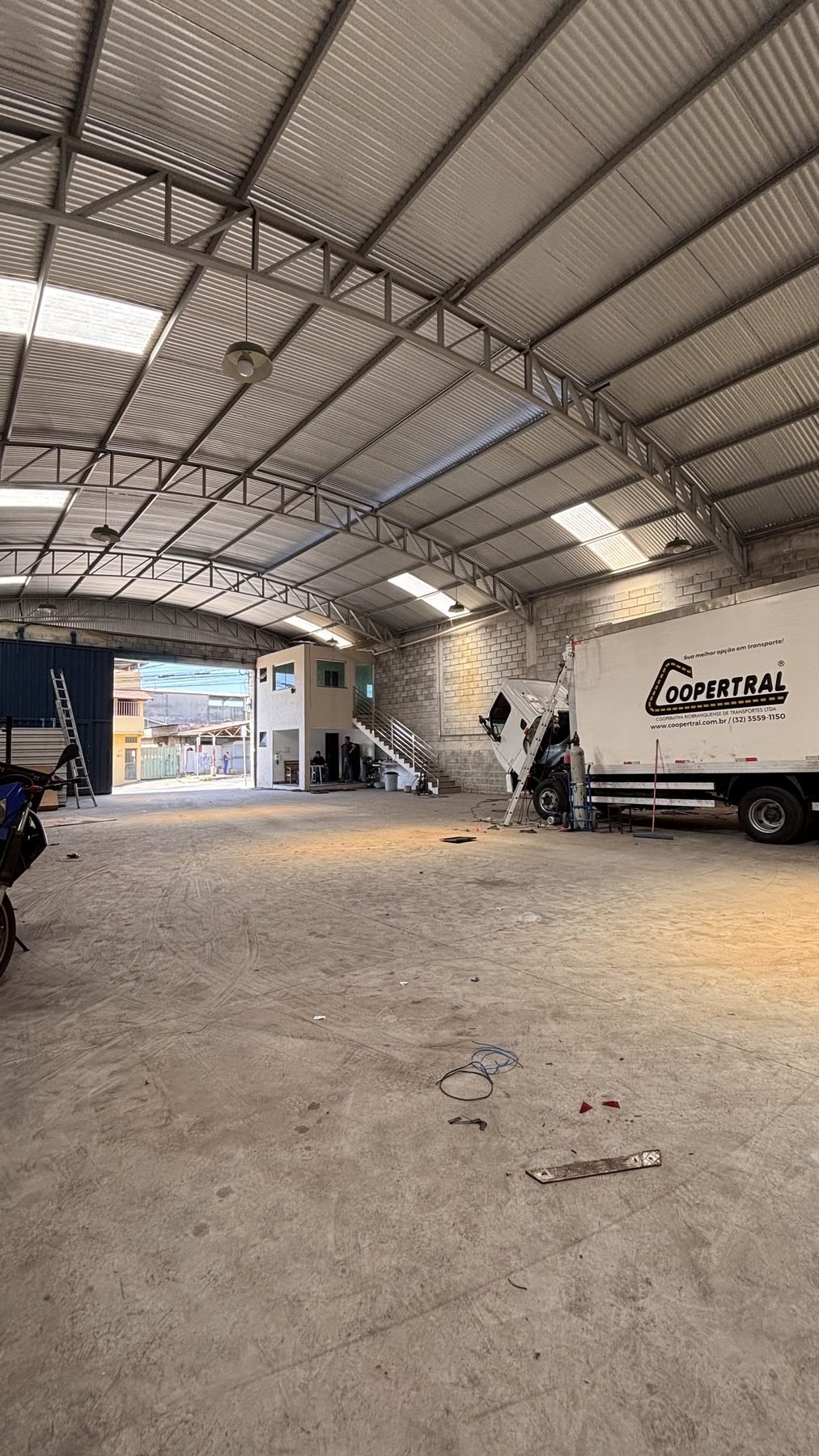Interior do galpão da ThermoLider BH com portão aberto e caminhão de cooperativa em atendimento